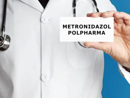 Lekarz w białym kitlu trzyma kartkę z napisem "METRONIDAZOL POLPHARMA". Metronidazol bez recepty to lek, który może pomóc w leczeniu infekcji.