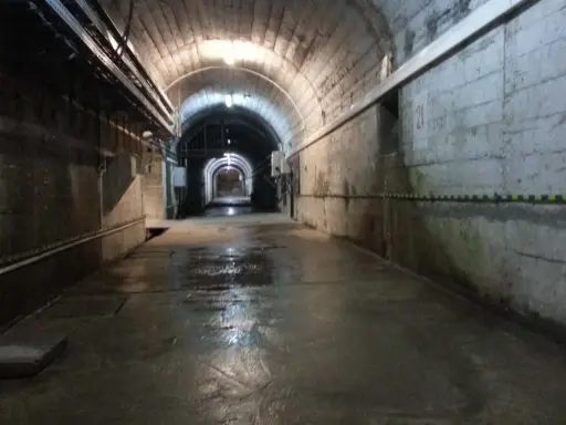 Wnętrze tunelu podczas zwiedzania elektrowni Solina. Mokra posadzka odbija światło lamp.