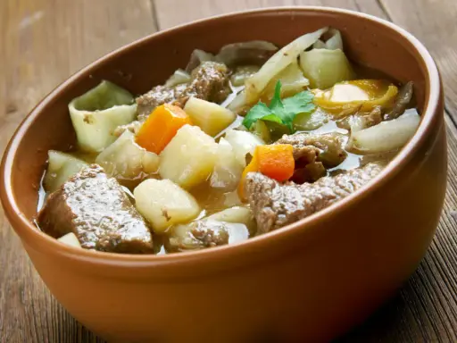Un copieux plat typique des Pyrénées, un ragoût de bœuf avec pommes de terre et carottes, servi dans un bol en terre cuite.