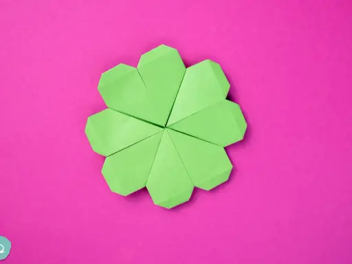 Ein grüner Origami-Glücksbringer, der wie ein Kleeblatt aussieht, auf einem pinken Hintergrund.