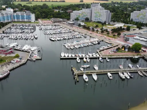 Viele Segelboote und Yachten liegen im dampfenden Hafen von Damp. Moderne Gebäude säumen die Küste.