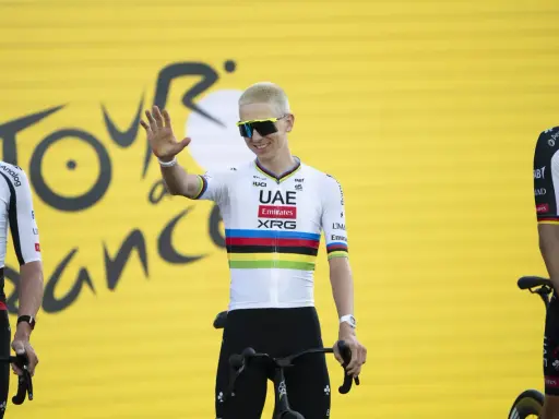 Radfahrer mit bunten Trikotfarben der Tour de France winkt fröhlich.