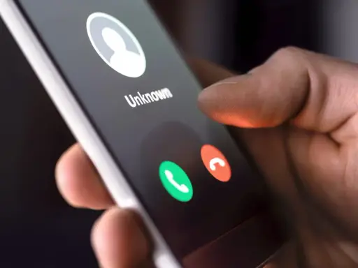 Dłoń trzyma smartfon z ekranem połączenia przychodzącego od nieznanego numeru. Dowiedz się, jak dzwonić z zagranicy do Polski na komórkę.