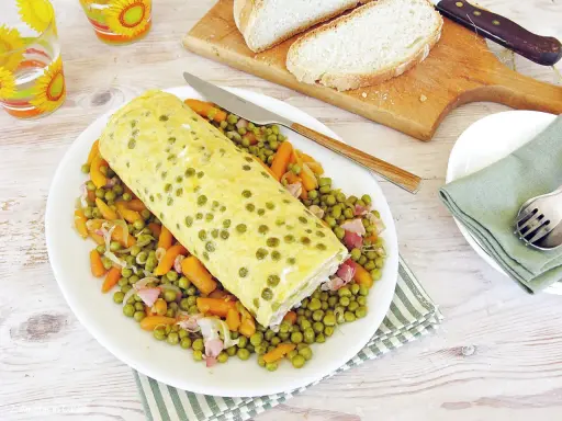 Rotolo di frittata dorato adagiato su un letto di piselli e carote. Un piatto semplice e gustoso, perfetto per un pasto leggero.