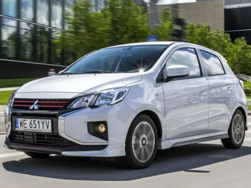 Srebrny Mitsubishi Space Star z czerwonymi akcentami na grillu i zderzaku jedzie po drodze.