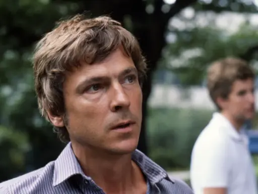 Carl Ivar Nilsson, en man med rufsigt hår och en randig skjorta, tittar bort. En annan man syns suddigt i bakgrunden.