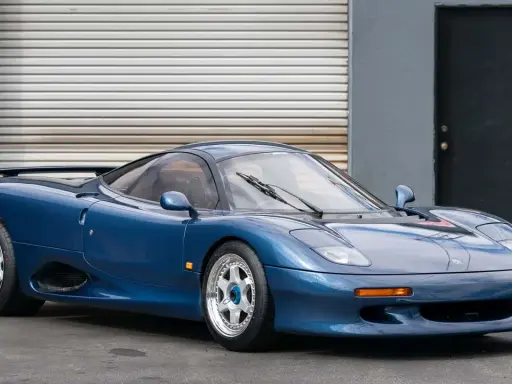 Blauer Jaguar XJR-15 Sportwagen mit auffälligem Heckspoiler und glänzenden Felgen, bereit für die Rennstrecke.