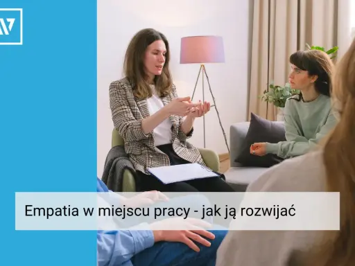 Kobieta w marynarce tłumaczy coś dłonią, siedząc naprzeciwko słuchaczy. Widać, że to rozmowa o empatii w pracy, która buduje lepsze relacje.