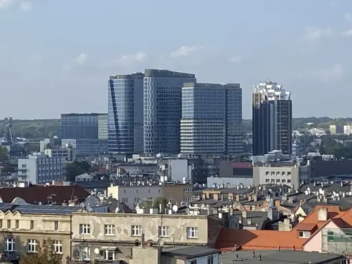 Nowoczesne wieżowce górują nad dachem kamienicy w największym mieście w Polsce.