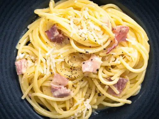 Spaghetti Carbonara mit herzhaftem Speck, cremig und mit frisch geriebenem Parmesan bestreut. Ein Klassiker, der immer schmeckt.