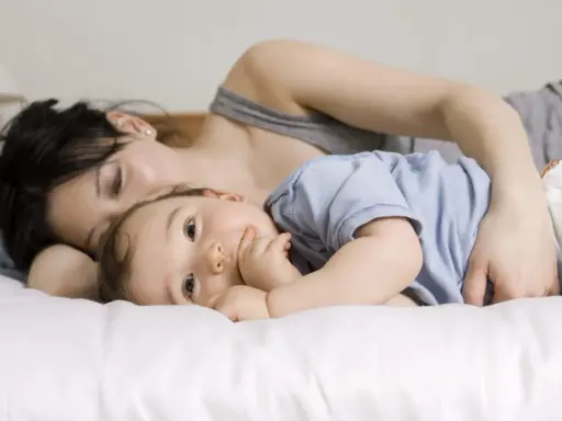 Mama tuli roczne dziecko do snu, przytulając je blisko.