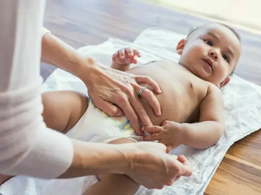 Mama sprawdza brzuszek maluszka, martwiąc się, że dziecko nie sika od 24 godzin.