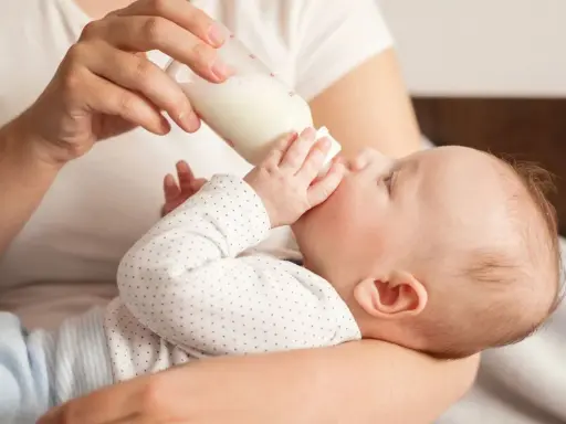 Dziecko pije mleko z butelki. Od kiedy mleko krowie zamiast modyfikowanego, maluch rośnie jak na drożdżach.
