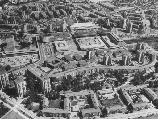 Luftaufnahme einer Siedlung mit vielen Hochhäusern und Wohnblöcken, die die Idee der autogerechten Stadt widerspiegelt.