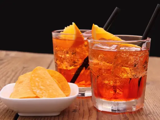 Dwa orzeźwiające drinki z pomarańczą i słone chipsy. Idealny aperitif, by rozpocząć wieczór.
