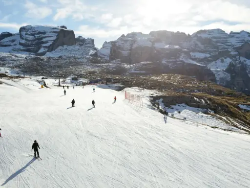 Narciarze szusują po ośnieżonym stoku w Dolomitach. Idealne miejsce, gdzie na narty we Włoszech, z majestatycznymi górami w tle.