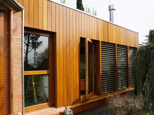 Modern house with ventanales grandes para casas, madera y ladrillo. Un árbol frondoso cuelga sobre la estructura.