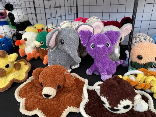 A variety of colorful, crocheted stuffed animals including elephants, ducks, a giraffe, and a purple creature.