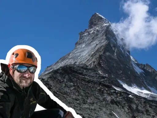 Uśmiechnięty alpinista w kasku i goglach na tle majestatycznego Matterhornu. To jego wejście na Matterhorn, cel zdobyty!