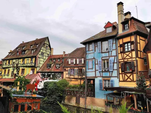 Case colorate e a graticcio lungo un canale, un'incantevole scena tra le città europee da visitare, con decorazioni natalizie.