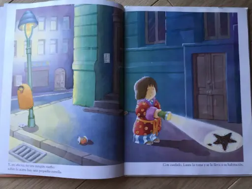 Laura, protagonista de "la estrella de laura cuento", ilumina con su linterna una estrella caída en la acera.