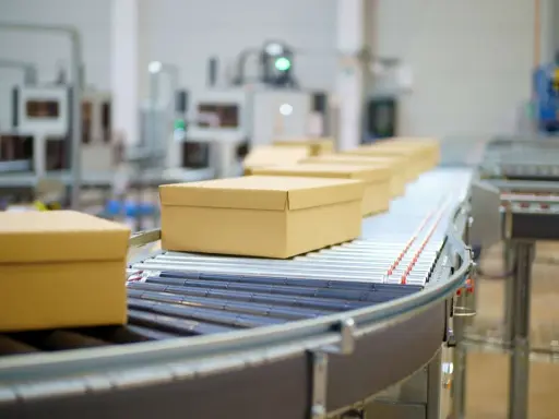 Pudełka na taśmie transportowej w magazynie ecommerce.