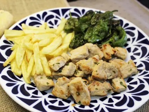 Raxo gallego con patatas fritas y pimientos de Padrón. Un plato contundente y delicioso.