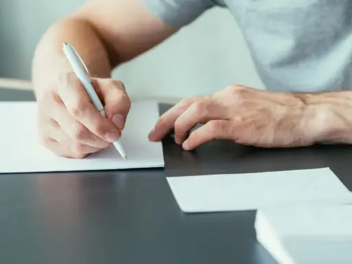 Mężczyzna pisze ręcznie list motywacyjny, przygotowując się do ważnego spotkania.