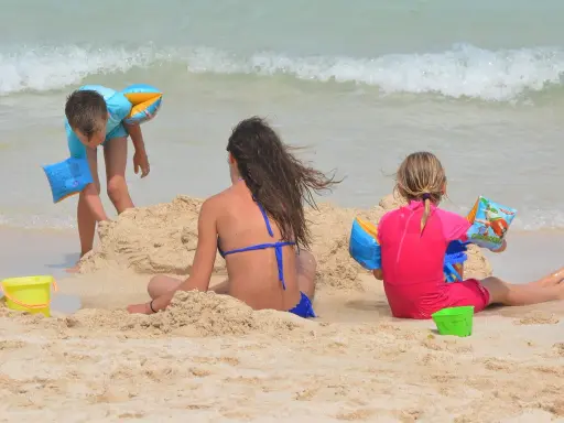 Bambini giocano sulla spiaggia, costruendo castelli di sabbia e godendosi il mare. Una giornata perfetta in una spiaggia per bambini.