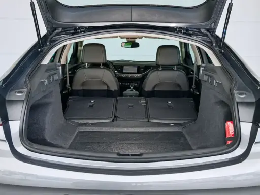 Maletero abierto de un Opel Insignia gris, mostrando asientos traseros abatidos y espacio de carga. Ideal para conocer las medidas del maletero.