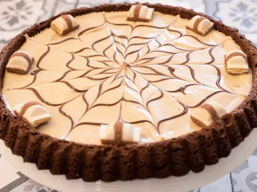 Torta Kinder Bueno con decorazione a ragnatela di cioccolato e pezzi di wafer.