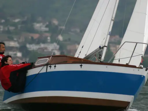 Couple en action sur un voilier transportable hauturier, profitant d'une navigation par temps frais.