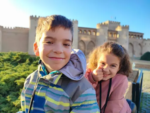 Dos niños sonríen frente al Palacio de la Aljafería, un lugar genial que ver en Zaragoza con niños.