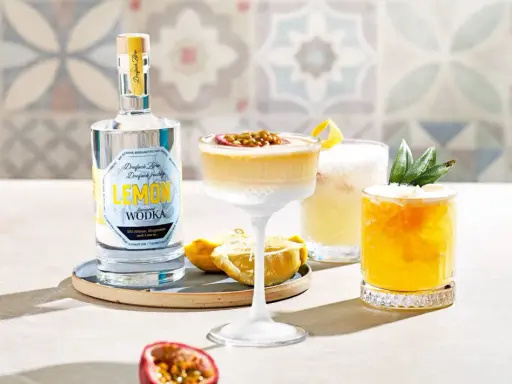Erfrischender Vodka Sour mit Passionsfrucht und Zitrone, daneben ein weiterer Cocktail mit Ananas. Eine Flasche Zitronen-Wodka steht bereit.