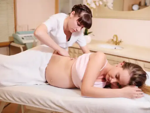 Relaksacyjny masaż w ciąży dla przyszłej mamy. Terapeuta delikatnie masuje plecy, przynosząc ulgę.