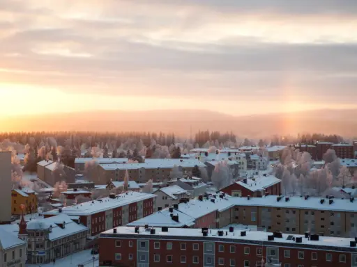 Vintermorgon i Boden, Sverige. Solen går upp över ett snötäckt landskap med hus och träd.
