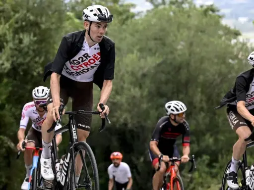 Radfahrer im Rennen bei der Dauphiné Rundfahrt. Ein Fahrer in weißem Trikot mit "AG2R CITROEN" Aufschrift fährt bergauf.