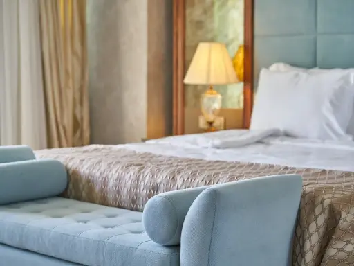 Elegancka sypialnia hotelowa z wygodnym łóżkiem i sofą. Spełnia wszelkie **hotel 4 gwiazdki wymagania** dotyczące komfortu i stylu.