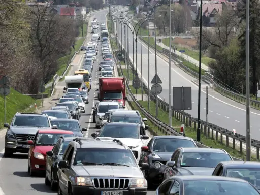 Korek na drodze, jak węzeł gordyjski, zablokował ruch. Samochody stoją w długiej kolejce, tworząc niekończący się rząd pojazdów.