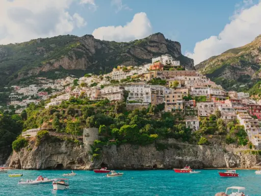 Positano, un gioiello da scoprire, perfetto per chi cerca cosa vedere a Napoli in un giorno. Case colorate aggrappate alla scogliera, mare azzurro e barche.