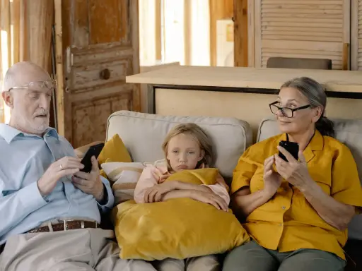Abuela paterna celosa mira con recelo mientras el abuelo y la nieta están absortos en sus teléfonos.