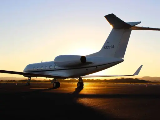 Ein weißer Privatjet steht im Sonnenuntergang auf dem Rollfeld. Verschiedene privatjets modelle sind auf dem Markt, aber dieser hier strahlt Luxus aus.