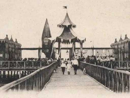 Antica passeggiata sui bagni isola di Cervia, con bambini che camminano sul pontile verso le strutture sul mare.