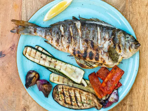 Gegrillte Dorade mit Zucchini, Aubergine, Paprika und Zwiebeln. Der frische Zitronenschnitz verspricht den vollen Dorade Geschmack.