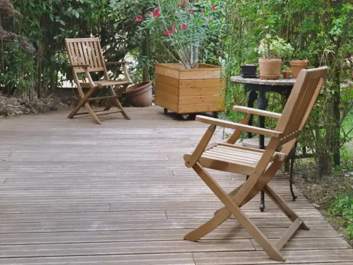 Deux chaises en bois sur une terrasse. Pour savoir comment protéger un meuble de l'humidité, pensez à un traitement hydrofuge.