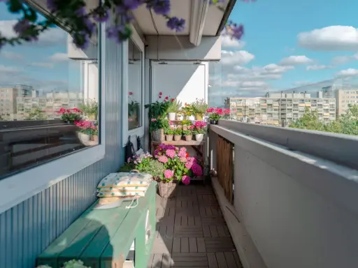 Uroczy balkon z drewnianą podłogą, zieloną ławką i mnóstwem kwiatów. Idealne miejsce, by odpocząć, gdy szukasz pomysłów, co na balkon zamiast płytek.