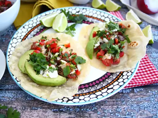 Två läckra tex mex-tacos med avokado, tomat, lök och koriander. Ett perfekt tex mex recept för en snabb och god middag.