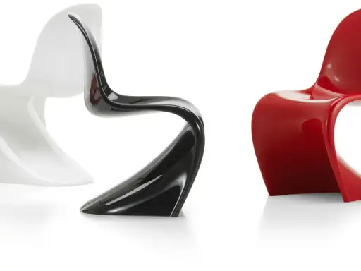 Tre sedie di design iconiche: una bianca, una nera lucida e una rossa brillante, con forme sinuose e moderne.