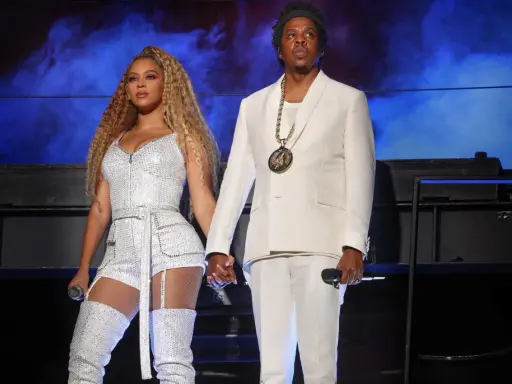 Beyoncé i Jay-Z, symbol sukcesu i majątku, na scenie w błyszczących strojach.