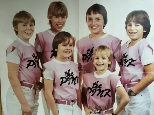 Sex glada pojkar i rosa tröjor med texten "the Pink" på. De ser ut att vara medlemmar i ett band.